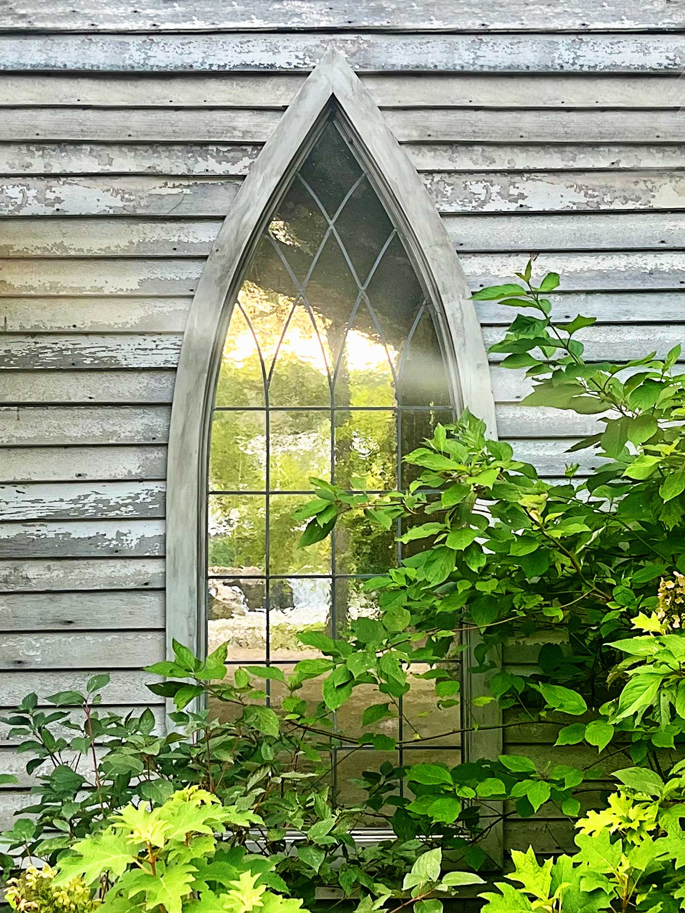 Finley River Chapel Window with greenery. In the background is the Finley River.