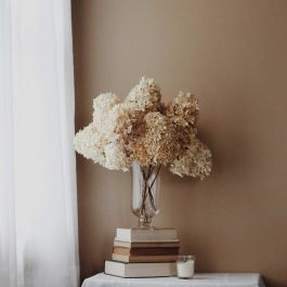 dried florals in a glass vase on books.