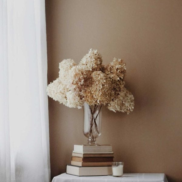 dried florals in a glass vase on books.