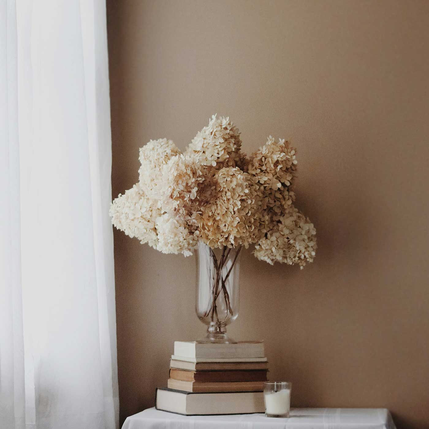dried florals in a glass vase on books.