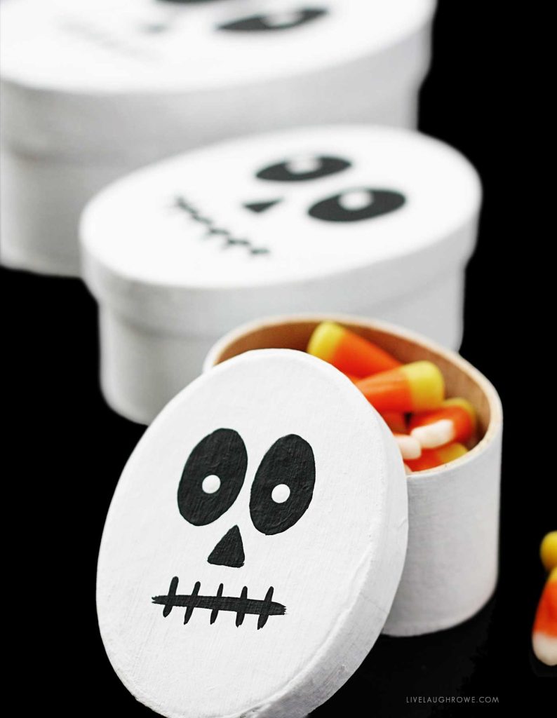 White oval Halloween treat box painted as a skeleton face on a black table