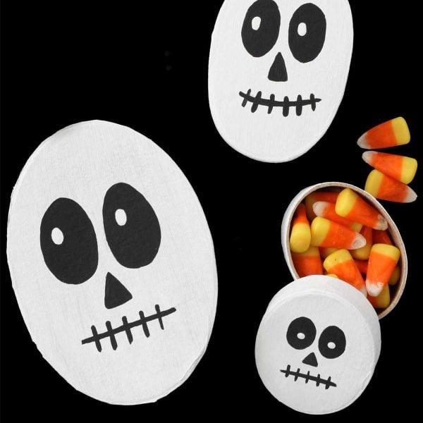 Finished DIY skeleton Halloween treat boxes with lids open to show candy inside