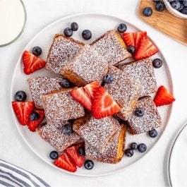 Golden brown Hawaiian Roll French Toast bites dusted with powdered sugar and served with maple syrup.