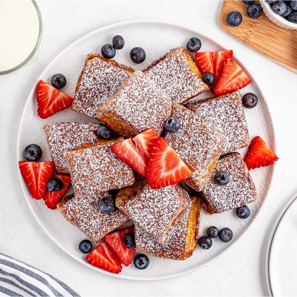 Golden brown Hawaiian Roll French Toast bites dusted with powdered sugar and served with maple syrup.