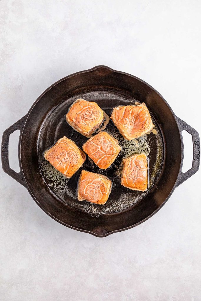 rolls placed in cast iron skillet for browning