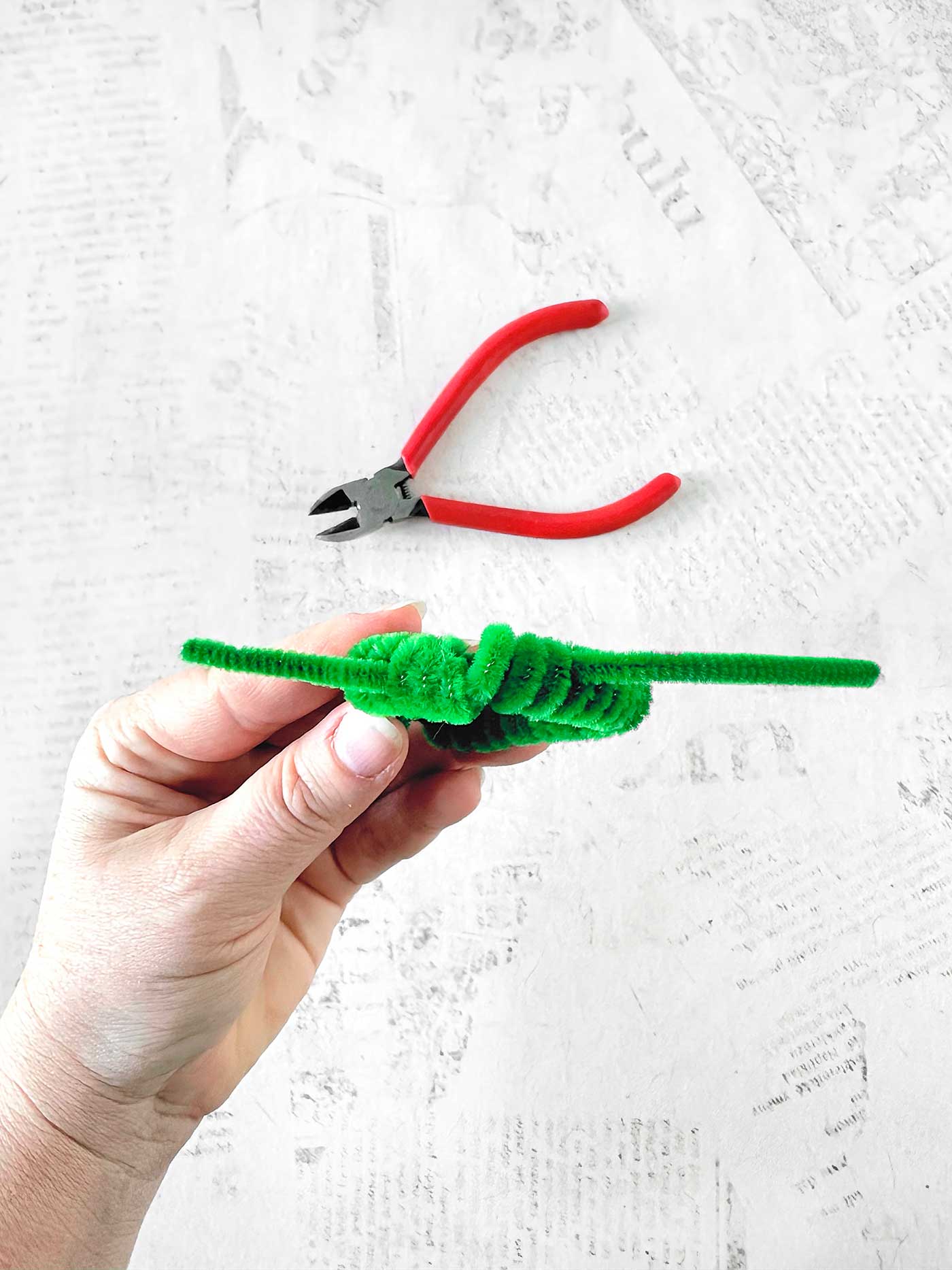 Hand securing the shape of round mini wreath.