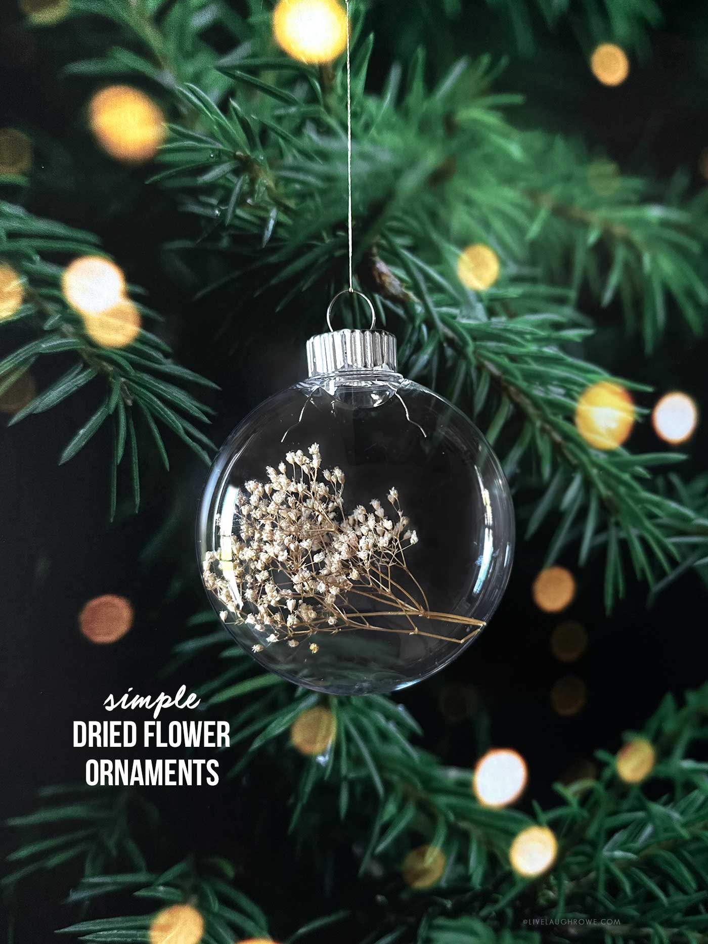 Finished ornament filled with dried baby’s breath hanging on a Christmas tree with warm glowing lights.