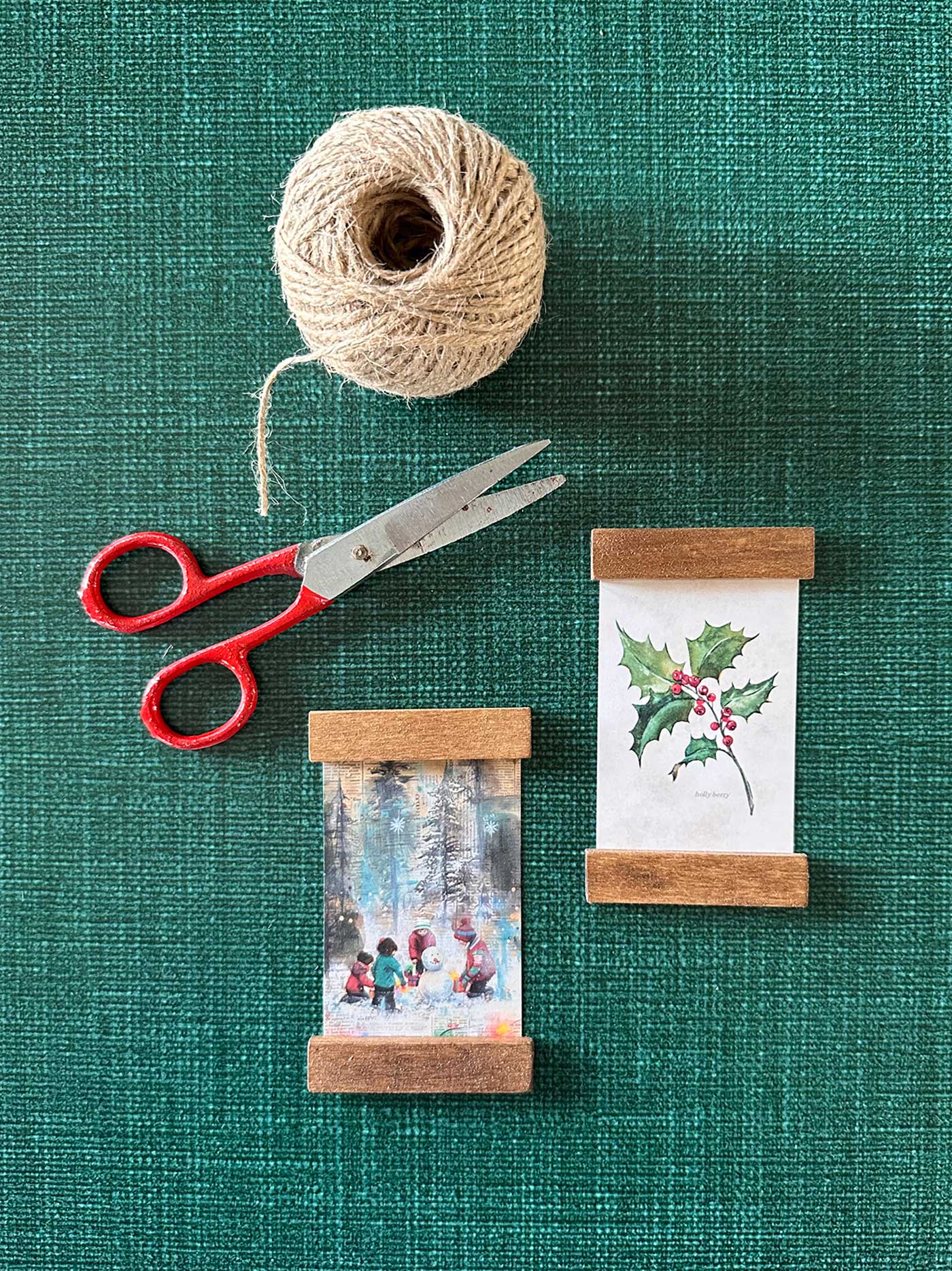 Finished mini poster hanger ornaments alongside scissors and twine, ready for hanging on the Christmas tree.
