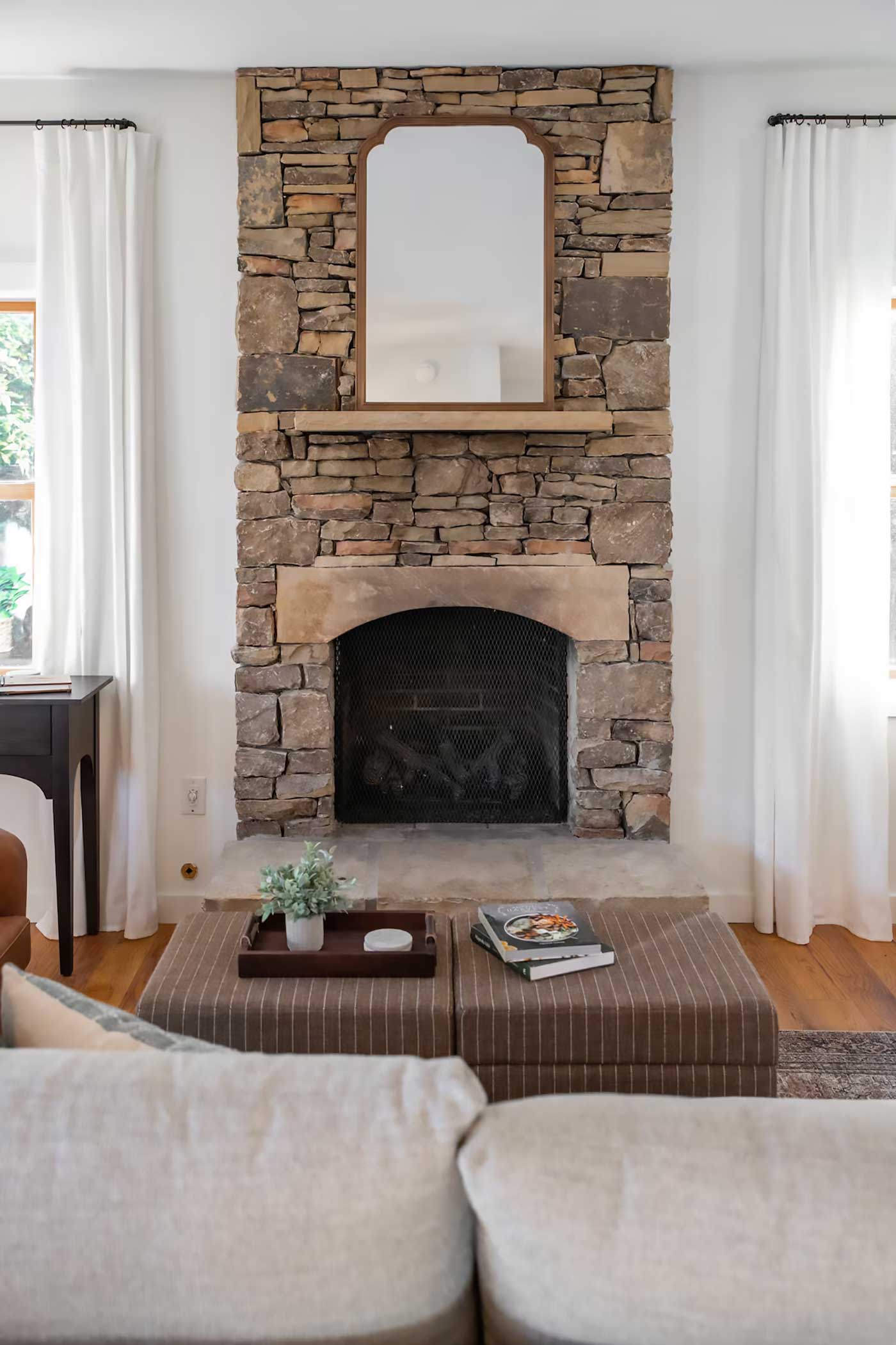 Cozy cabin living room with a stacked stone fireplace, neutral decor, and soft natural light in a Sevierville mountain cabin