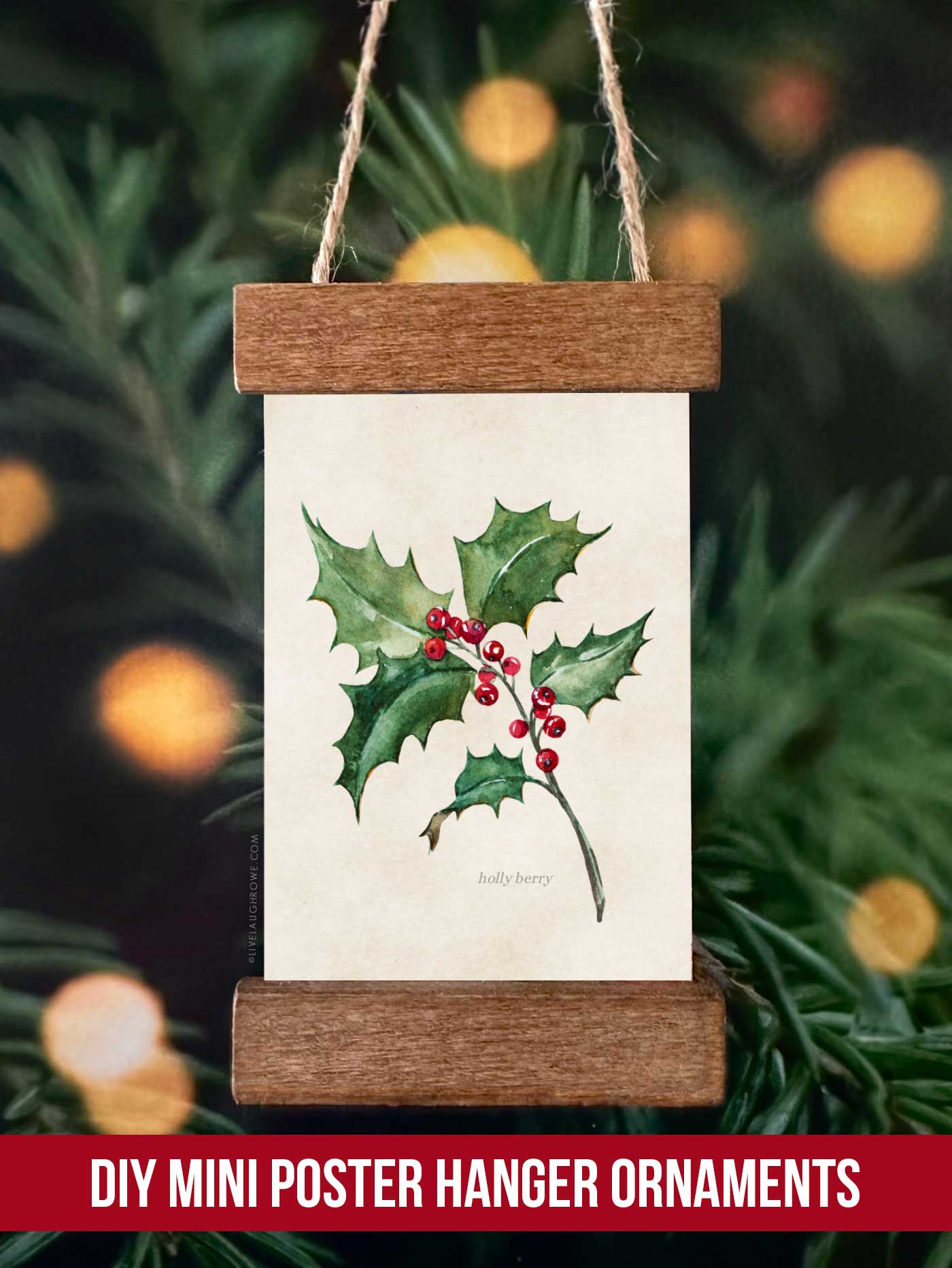 Festive ornament featuring a holly illustration displayed in a mini poster hanger ornament hanging on a Christmas tree.