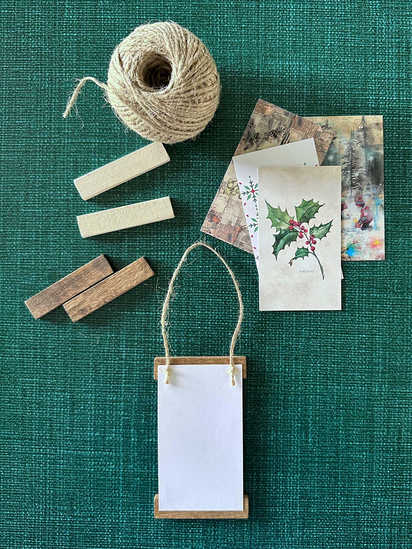 Back side of a mini poster hanger ornament showing twine attached to the top wood strip with glue.