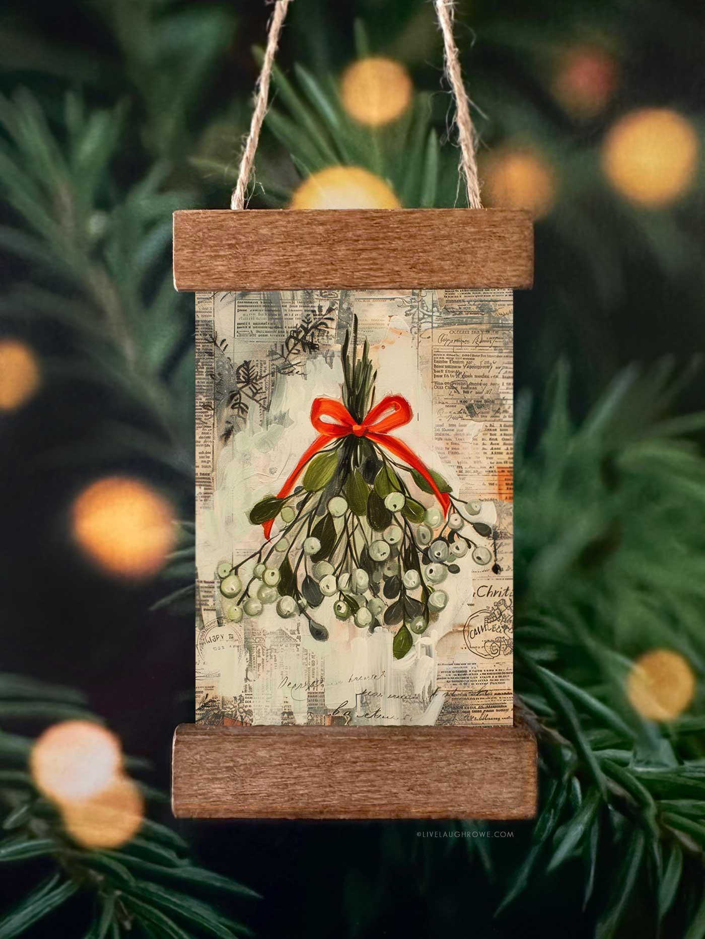 DIY Christmas ornament displaying mistletoe artwork in a mini poster hanger ornament with stained wood strips.