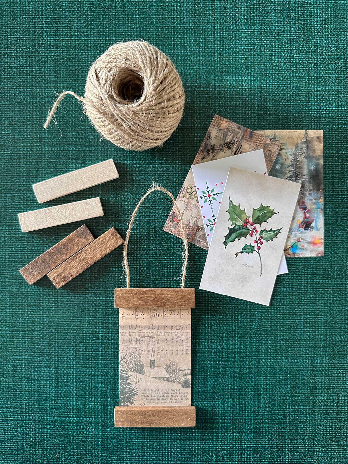 Handmade Christmas ornaments in progress, with wood strips and miniature prints ready to be assembled.