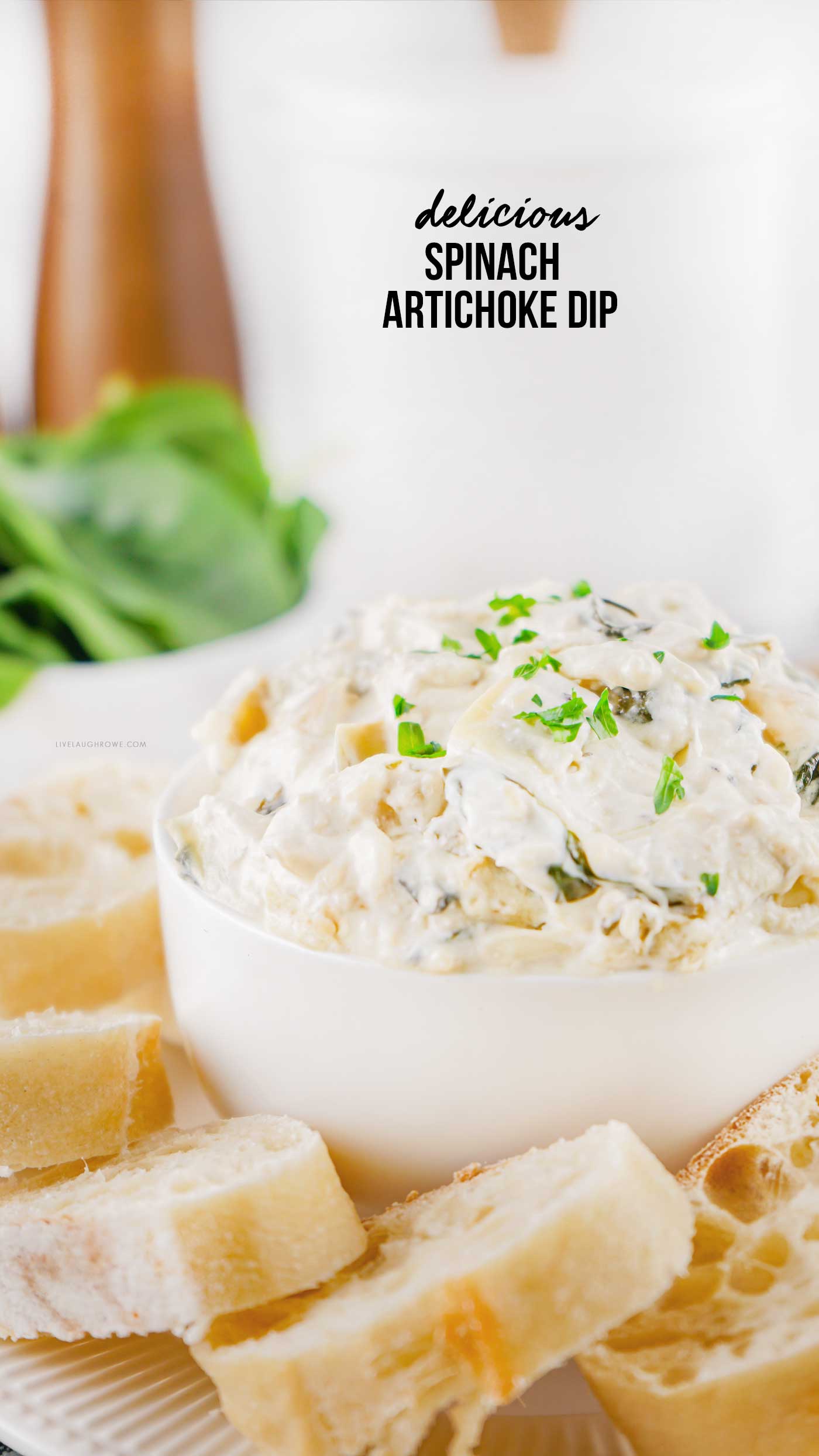 Creamy spinach artichoke dip served in a white bowl with sliced bread for dipping.