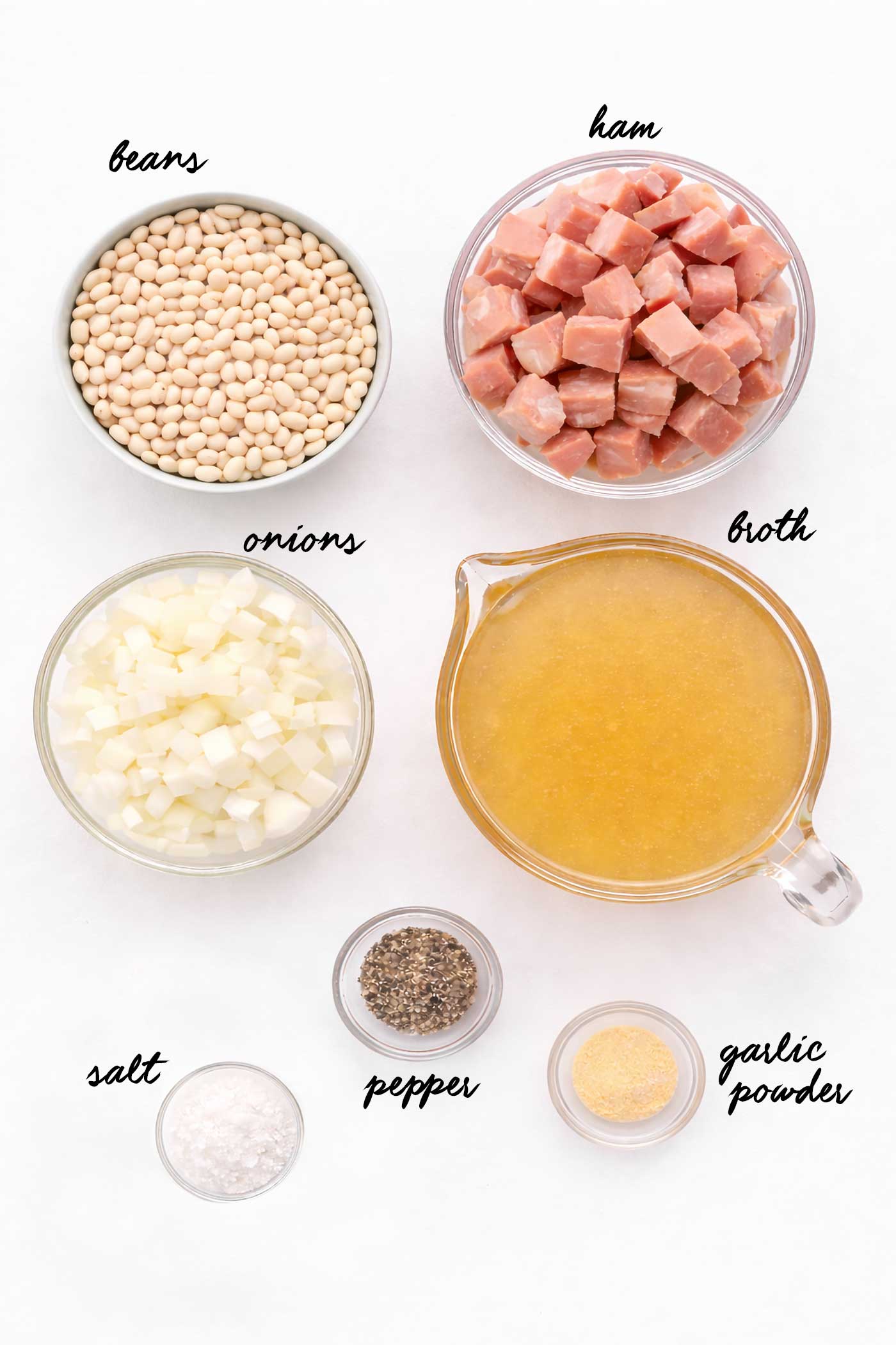 Ingredients for a slow cooker soup including dried beans, cubed ham, onion, and broth