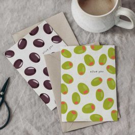 Olive-themed Valentine cards with green and black olive patterns styled beside a coffee mug