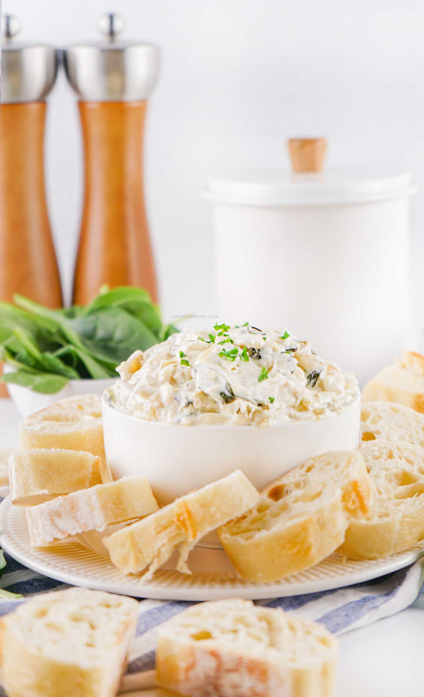 The best spinach artichoke dip for parties served with bread slices and fresh herbs.