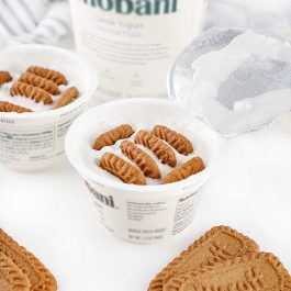 Greek yogurt cup with Biscoff cookies inserted to create a viral TikTok dessert before refrigerating.