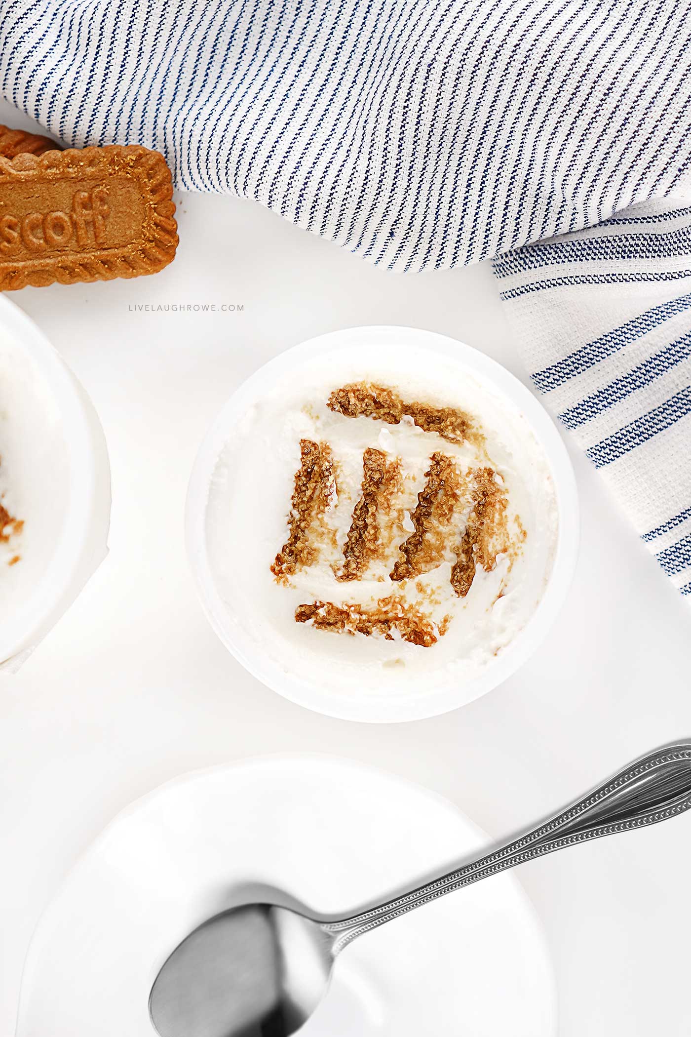 Top view of no-bake Japanese cheesecake made with Greek yogurt and Biscoff cookies, styled with a striped kitchen towel and spoon.