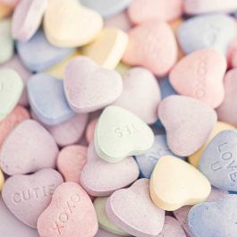 Close-up of pastel Valentine conversation heart candies in pink, yellow, blue, purple, and green.