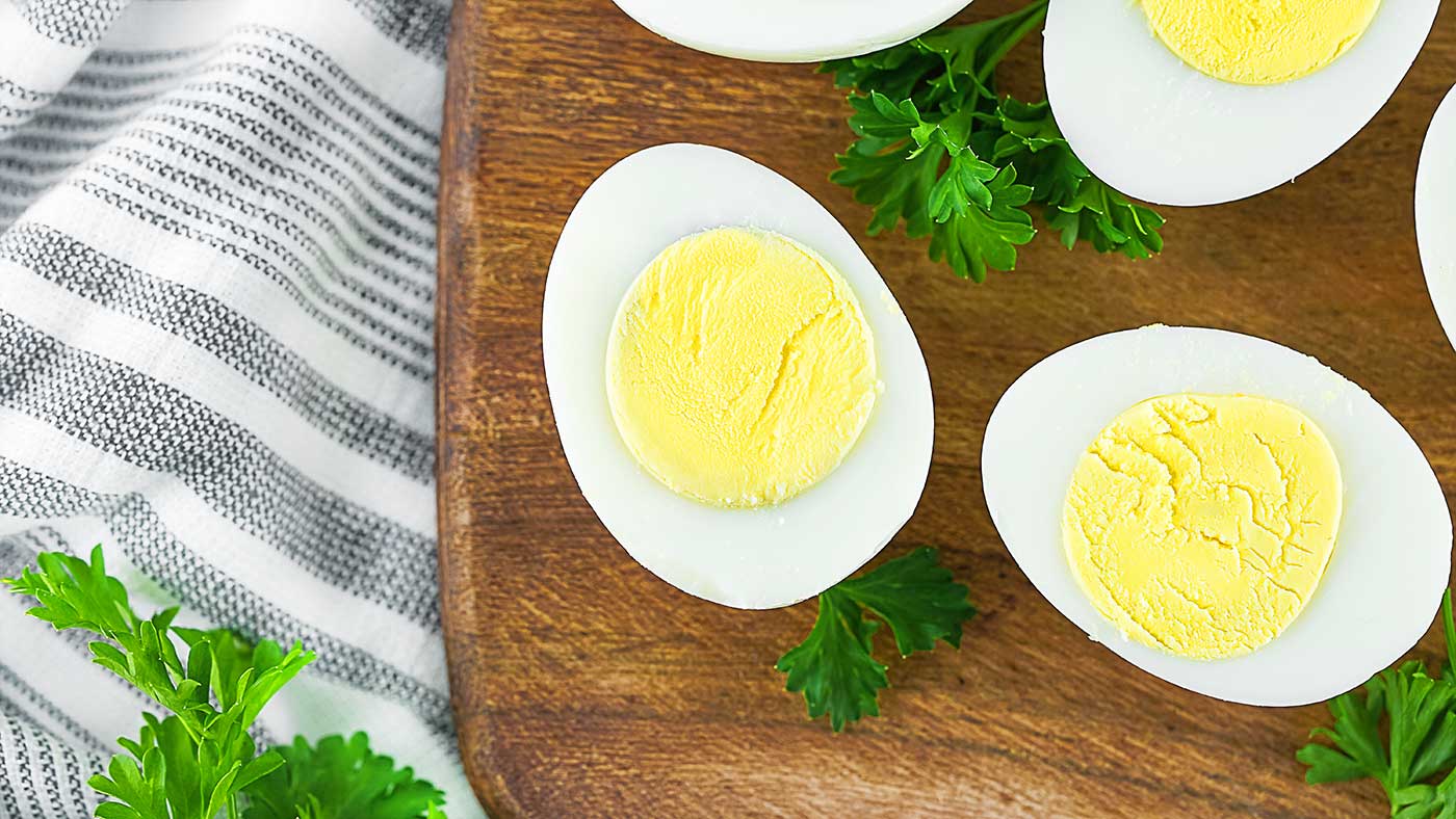 Sliced hard boiled eggs displayed on a rustic wooden cutting board