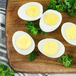 Hard boiled egg halves styled with fresh herbs on a wooden board