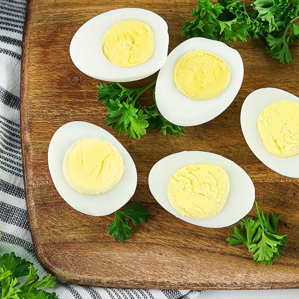 Hard boiled egg halves styled with fresh herbs on a wooden board