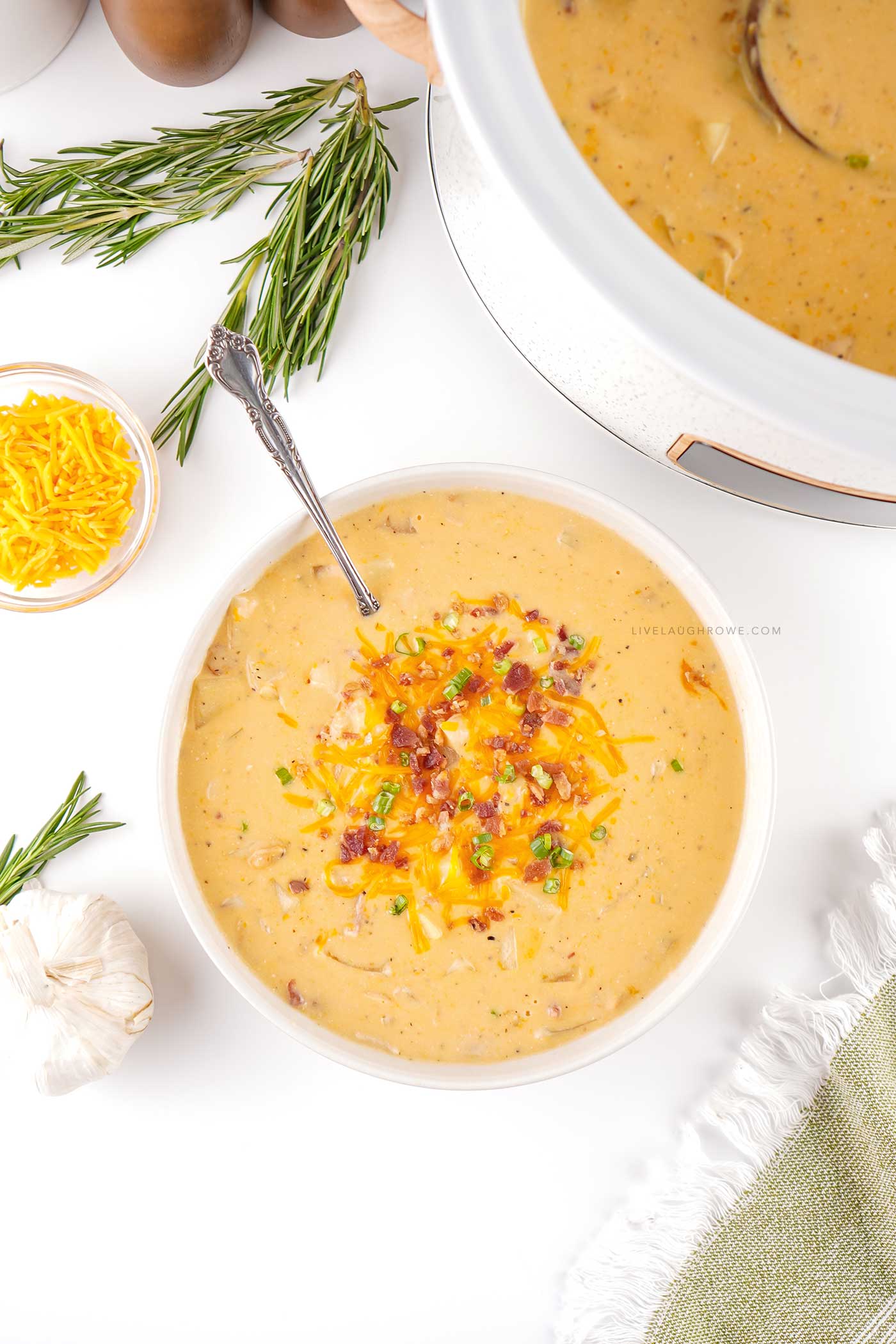 Overhead view of loaded crockpot crack potato soup with cheddar, bacon, and green onions.