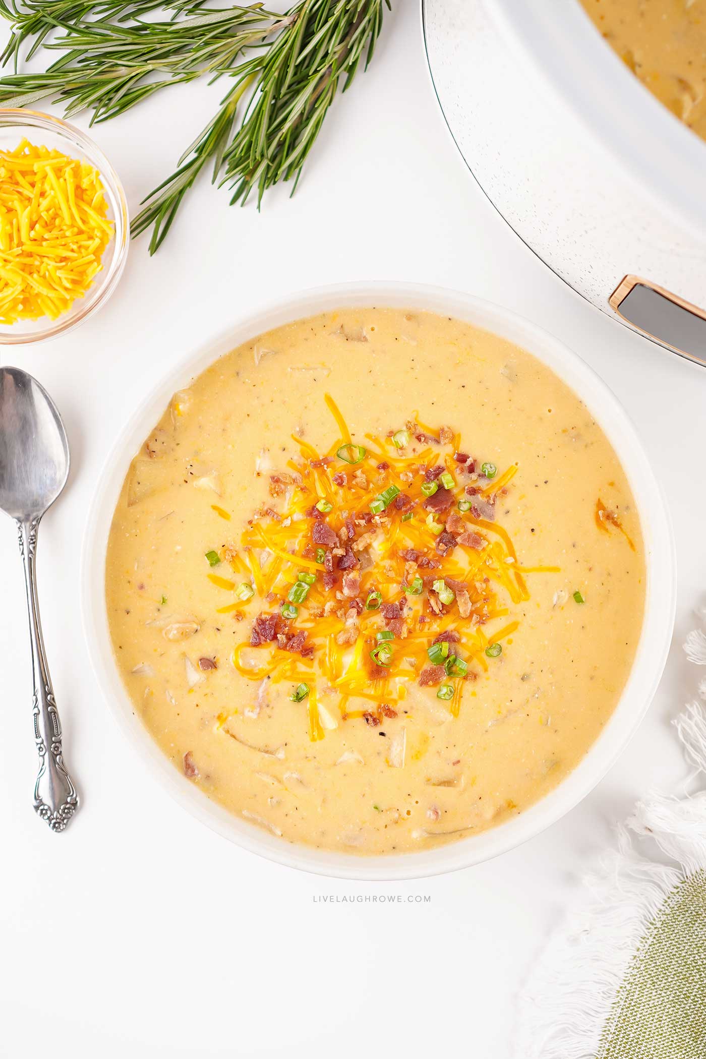 Creamy slow cooker crack potato soup served in a white bowl with shredded cheddar and crumbled bacon.