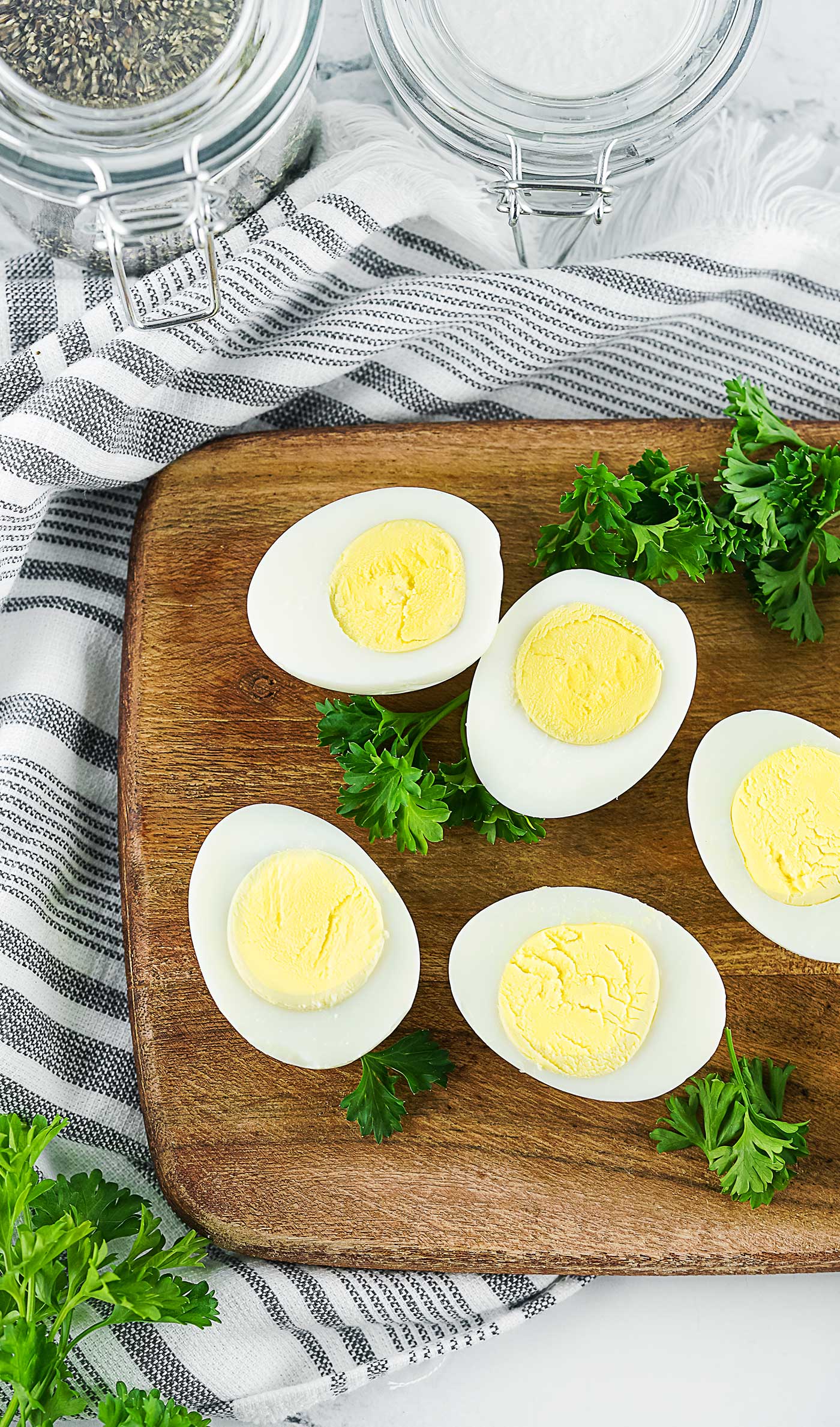 Hard boiled egg halves styled with fresh herbs on a wooden board