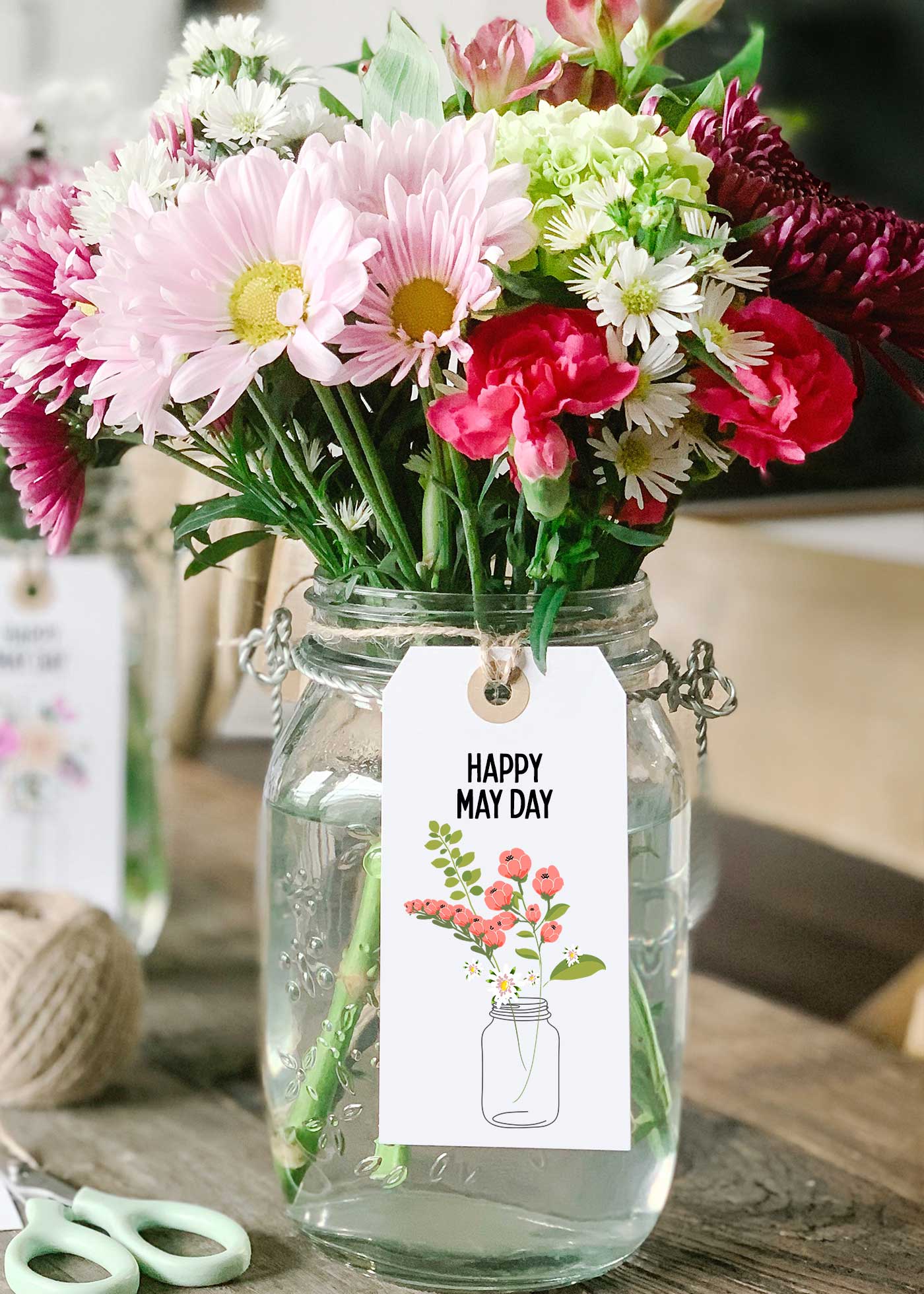 glass jar filled with fresh flowers and a Happy May Day printable tag tied to the front