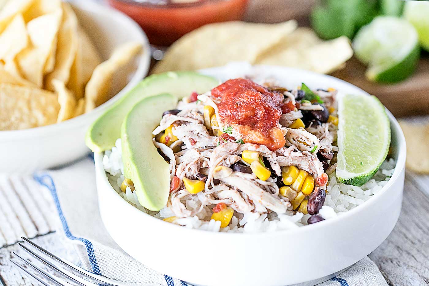 easy crockpot chicken burrito bowl with avocado, black beans, corn, rice, and salsa