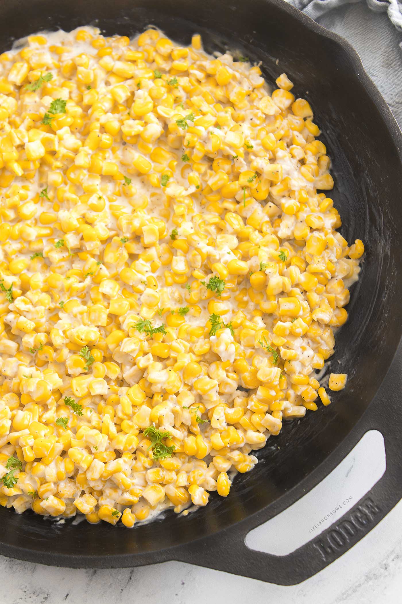 Creamy honey butter skillet corn cooking in a cast iron skillet with melted butter and corn