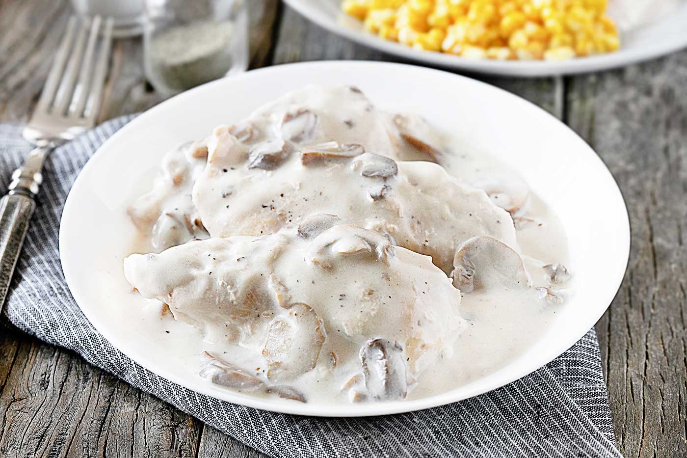 easy crockpot chicken and mushrooms served with creamy mushroom sauce on a white plate