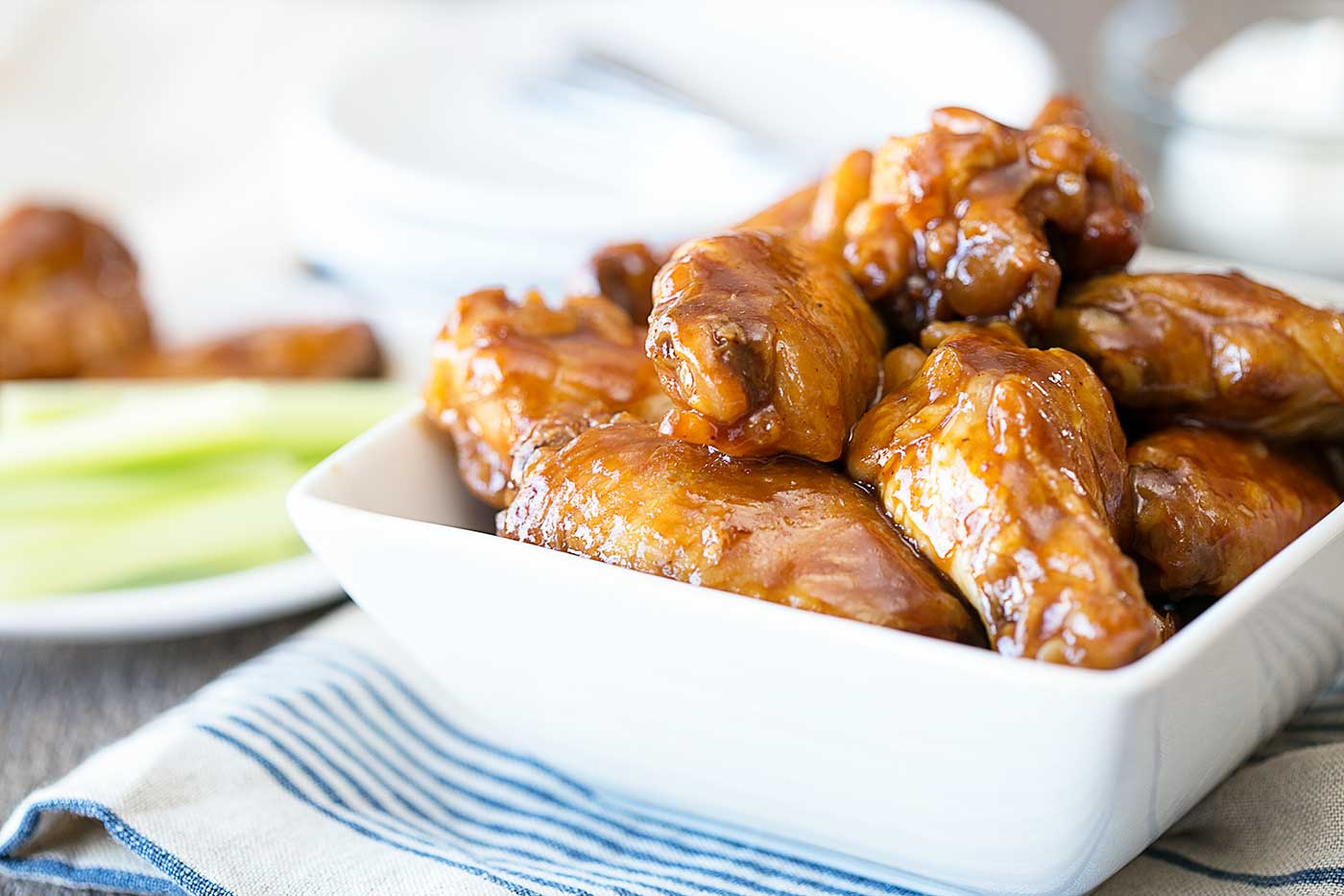 slow cooker BBQ chicken wings served in a white bowl with celery sticks on the side