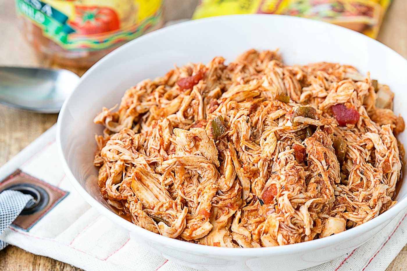 slow cooker salsa chicken served in a white bowl with shredded chicken, tomatoes, and peppers