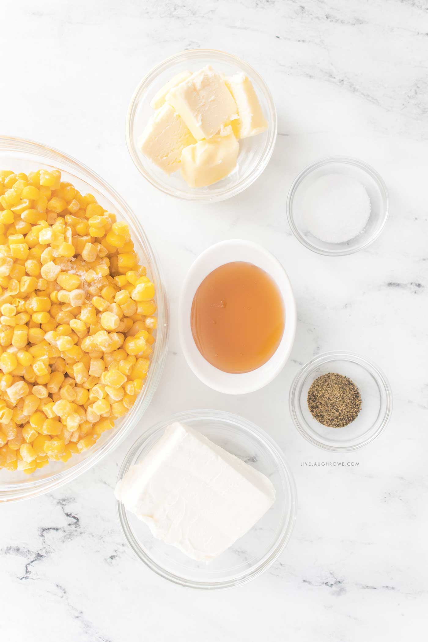 Honey butter skillet corn ingredients including frozen corn, butter, honey, cream cheese, salt, and pepper on a white surface