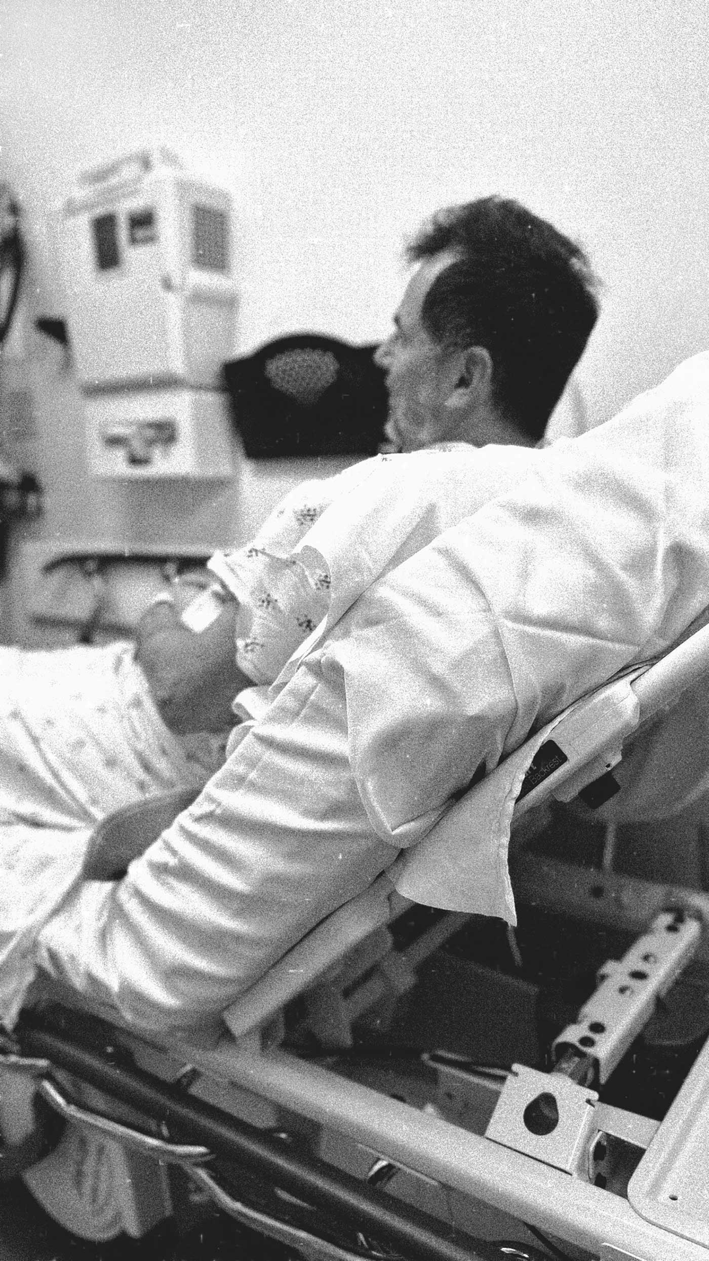 Black-and-white photo of a man resting in a hospital recovery room following a routine medical procedure.