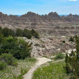 Square image of a narrow trail winding through the rugged terrain of Badlands National Park.