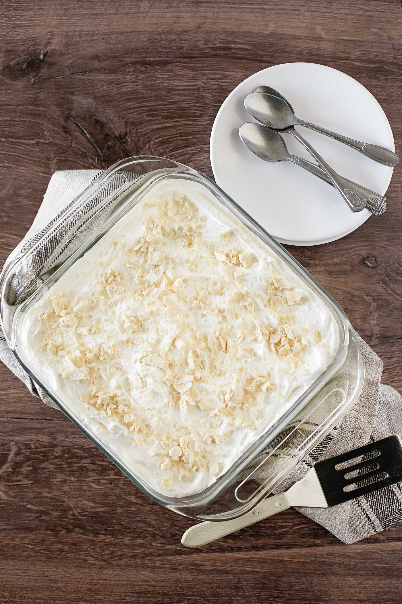 Overhead view of a chilled layered dessert in a glass baking dish topped with cracker crumbs.