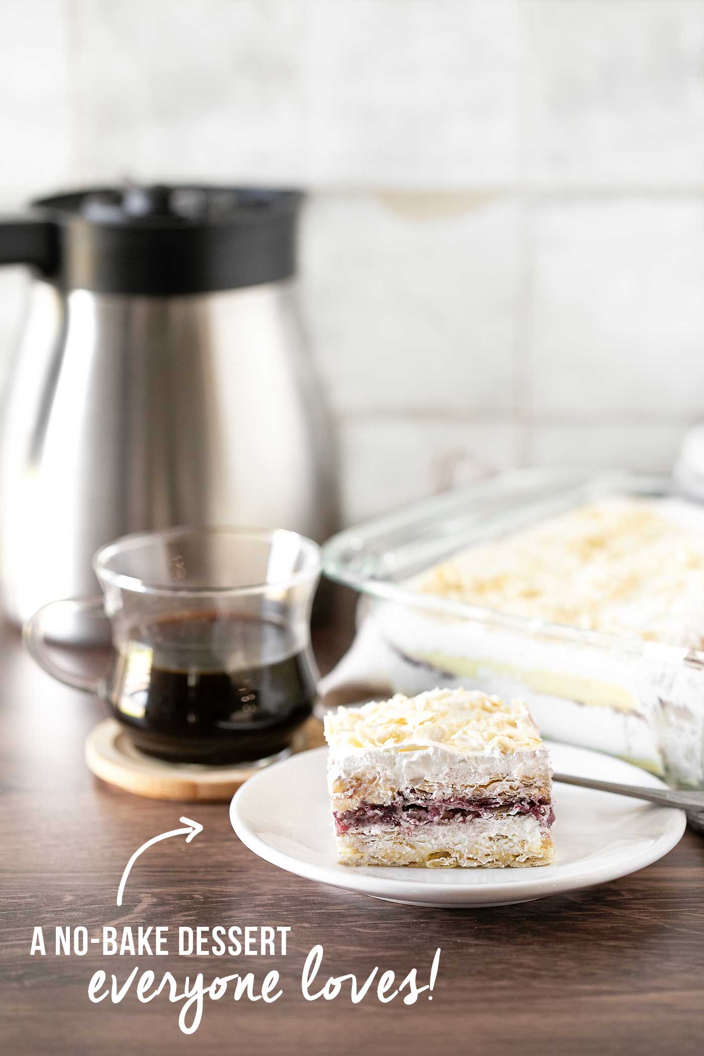 Layered dessert served on a white plate beside a baking dish and cup of coffee.