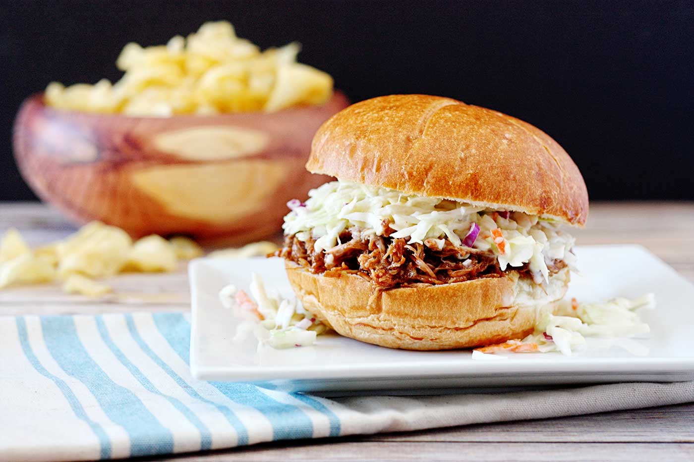 BBQ carnitas pork sandwich topped with creamy coleslaw and served on a soft bun.