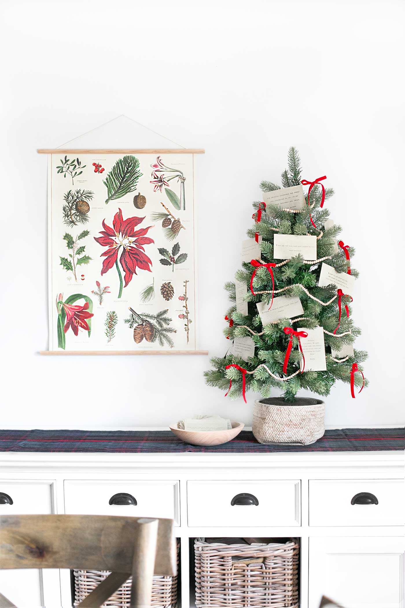 A tabletop Christmas Quote Tree decorated with vintage-inspired quote cards and red velvet ribbon displayed on a dining room buffet.