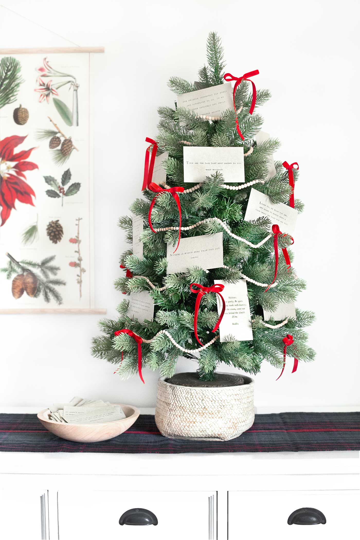 A tabletop Christmas tree decorated with quote cards, wooden bead garland, and red velvet ribbon.