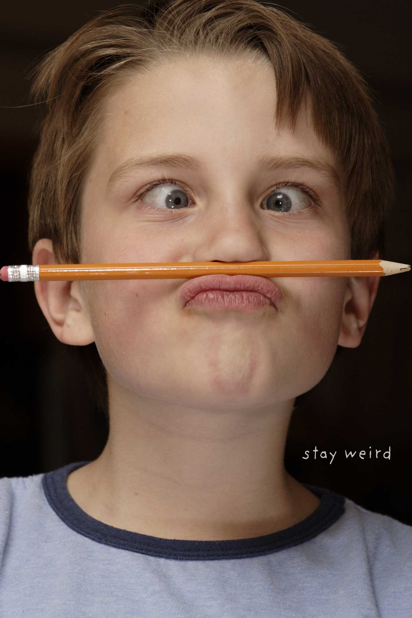 Child making a silly face while holding a pencil beneath his nose