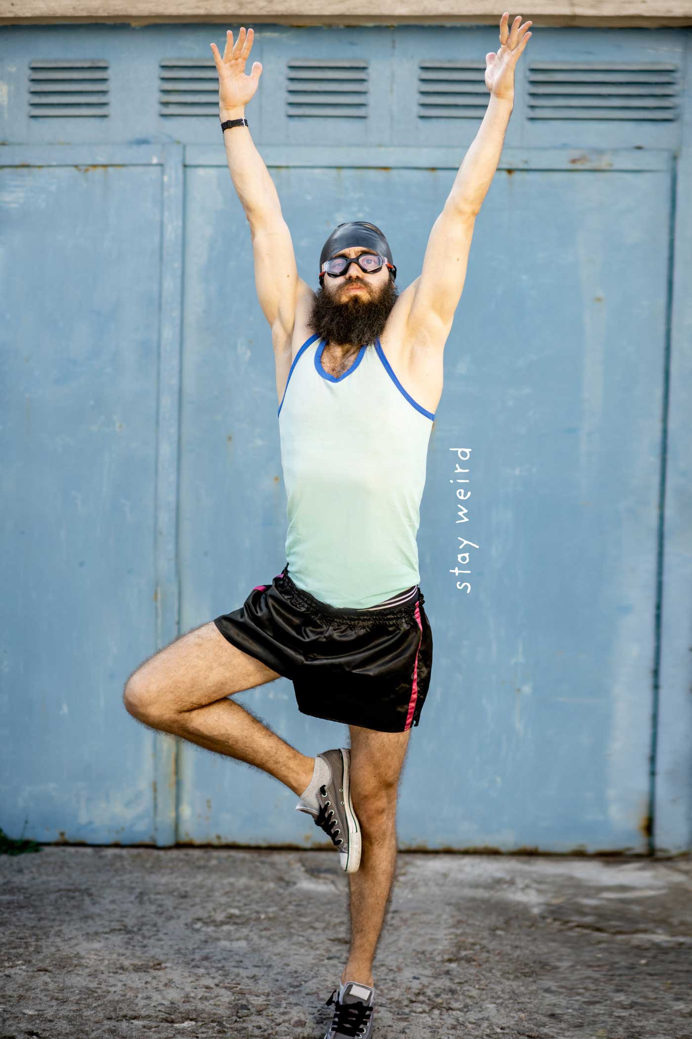 Bearded man balancing on one leg with both arms raised