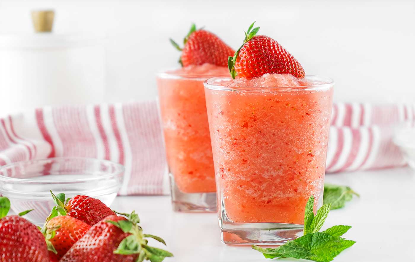 Easy Summer Recipe. Two glasses of strawberry agua fresca topped with fresh strawberries and served with mint and extra berries. 