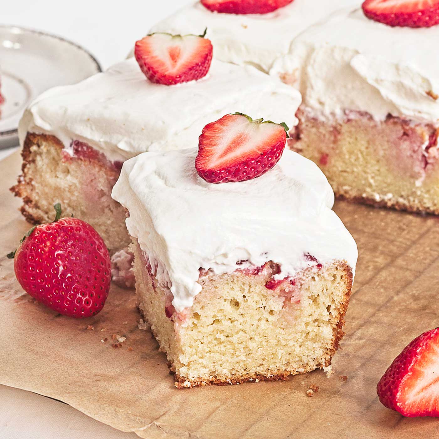 Slice of strawberry shortcake sheet cake with whipped cream, fresh berries, and strawberry filling
