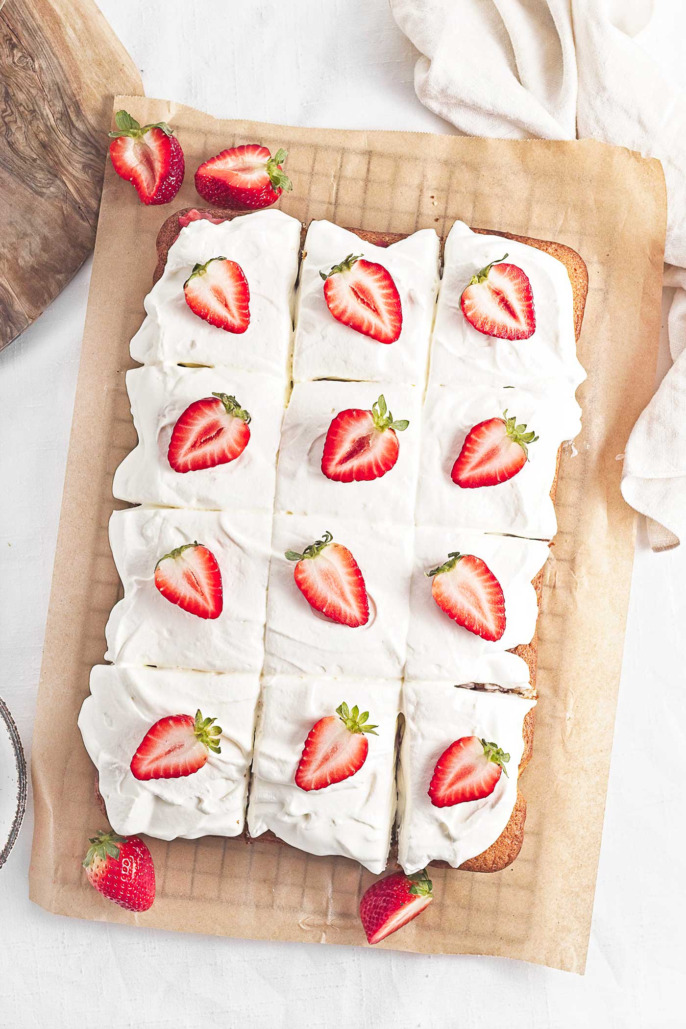 Strawberry easy summer dessert sliced into squares with whipped cream and fresh strawberries on top
