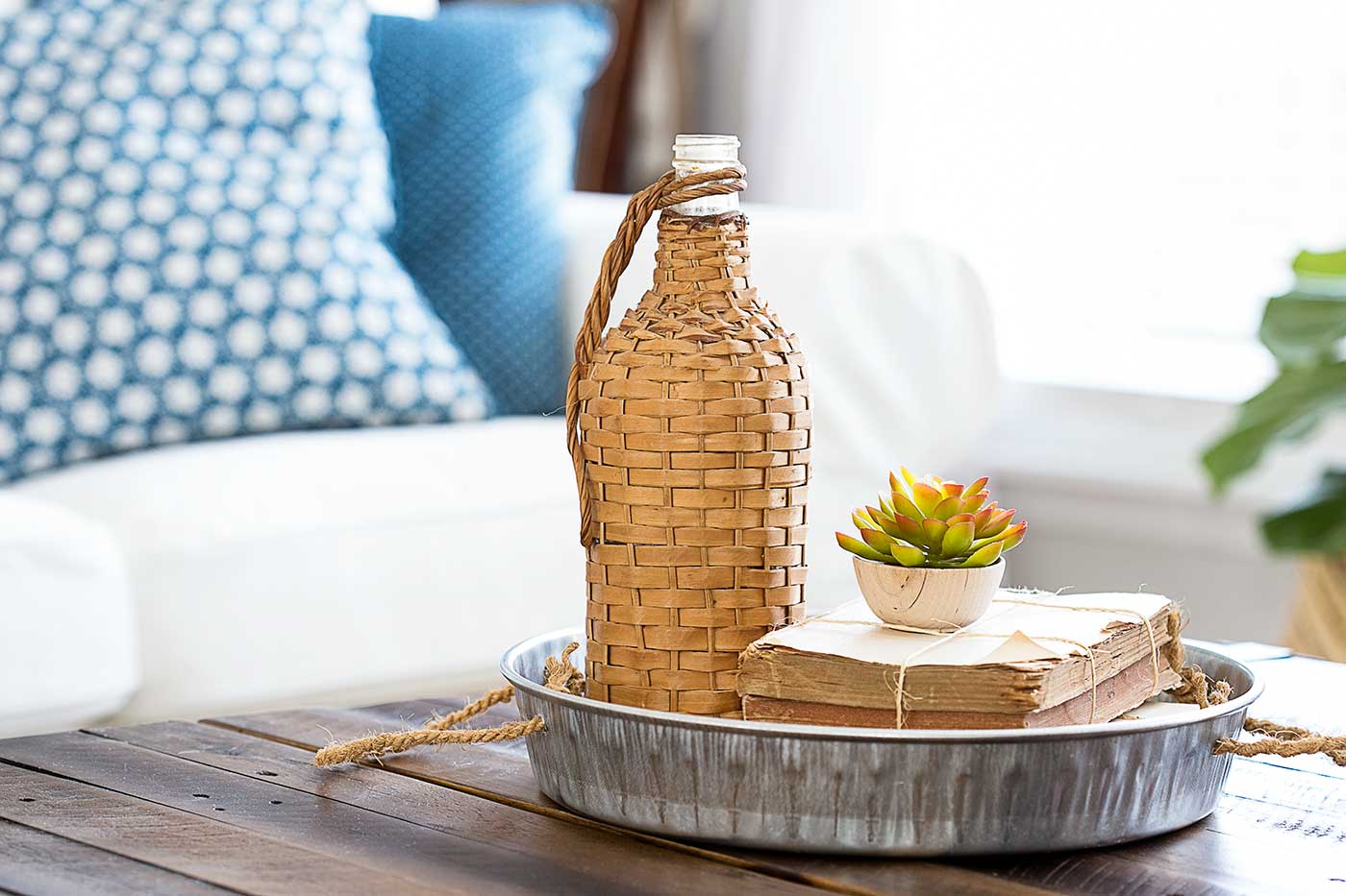 DIY project galvanized tray styled with a woven bottle, vintage books, and a small succulent